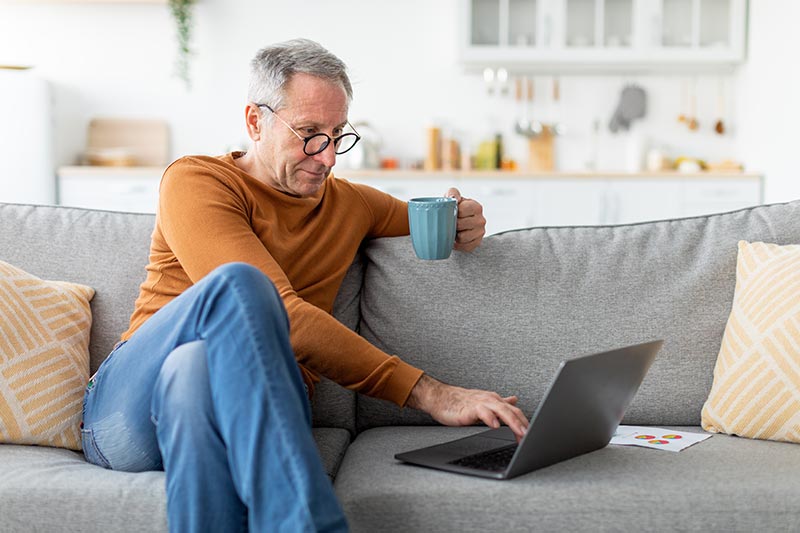 Guy browsing internet on laptop with coffee